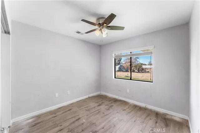 an empty room with window and ceiling fan