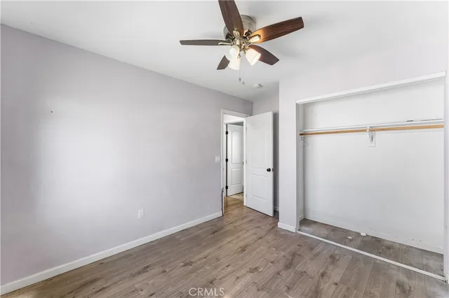 an empty room with wooden floor and fan