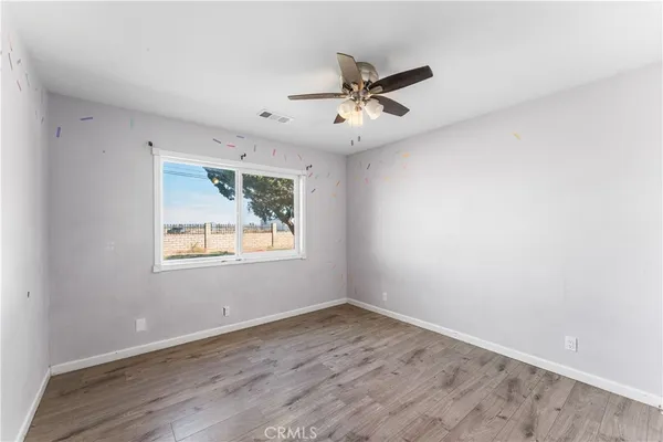 an empty room with wooden floor fan and windows
