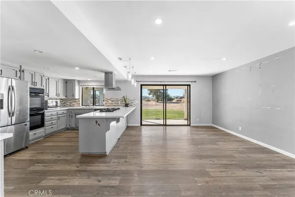 a large white kitchen with a refrigerator a sink dishwasher and a stove with wooden floor