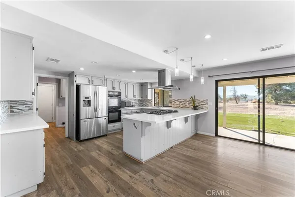 a large kitchen with kitchen island a large counter top space a sink stainless steel appliances and cabinets