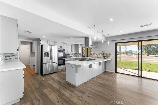 a large kitchen with kitchen island a large counter top space a sink stainless steel appliances and cabinets
