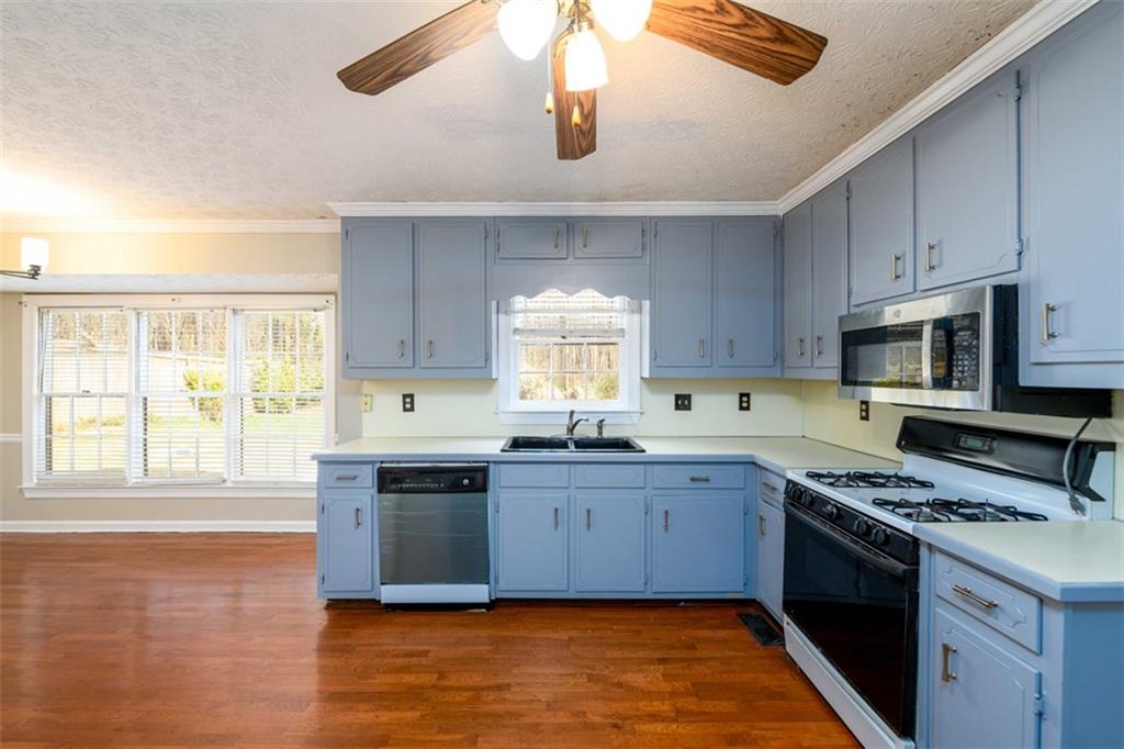 6420 Phillips Place Lithonia, GA 30058 - Photo 11 of 40 a kitchen with stainless steel appliances granite countertop a sink cabinets and wooden floor