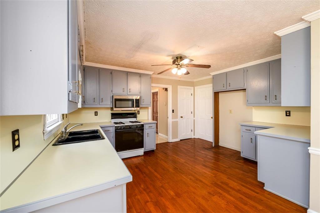 6420 Phillips Place Lithonia, GA 30058 - Photo 12 of 40 a kitchen with a refrigerator a stove top oven a sink dishwasher and wooden floor