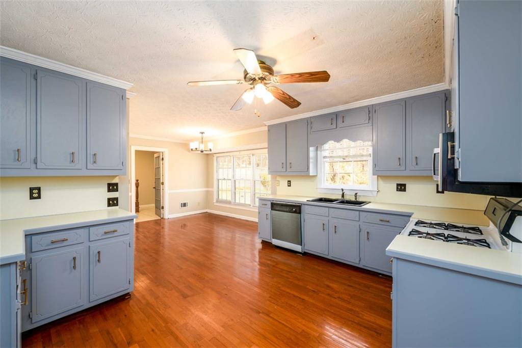 6420 Phillips Place Lithonia, GA 30058 - Photo 14 of 40 a kitchen with granite countertop a stove a sink dishwasher and a refrigerator with wooden floor