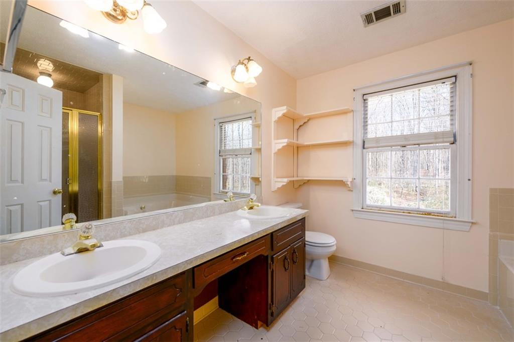 6420 Phillips Place Lithonia, GA 30058 - Photo 26 of 40 a bathroom with a sink a toilet a mirror and a window