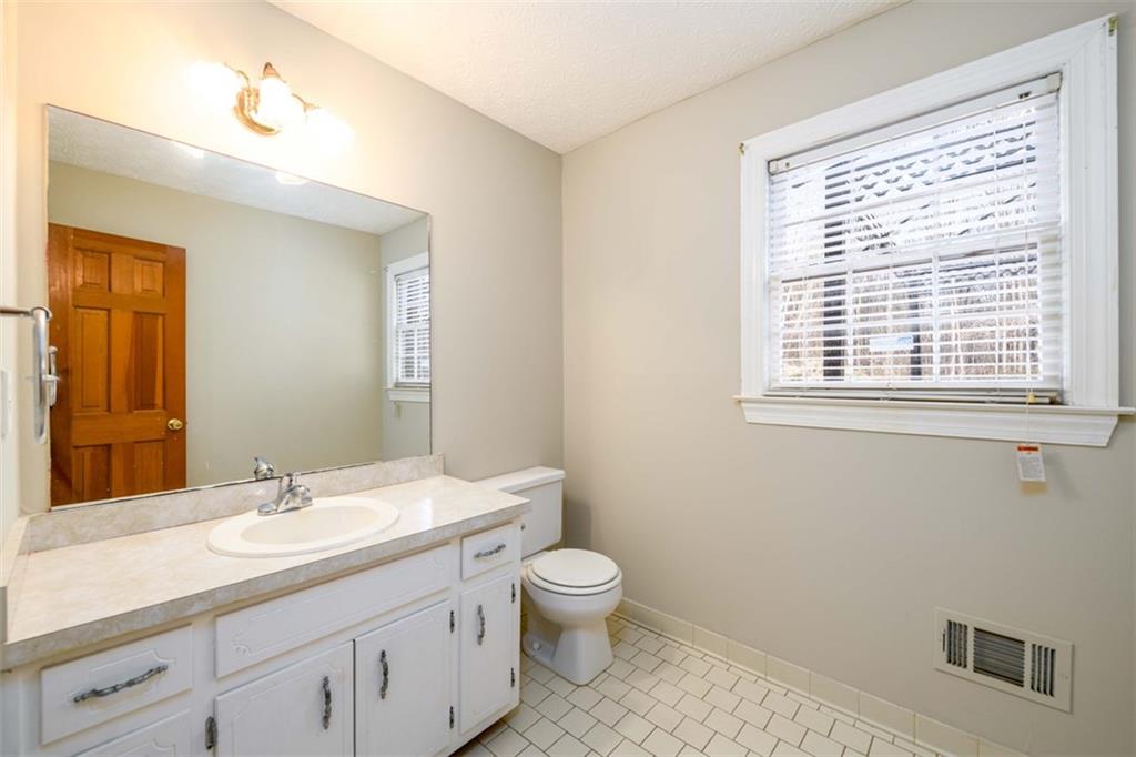 6420 Phillips Place Lithonia, GA 30058 - Photo 6 of 40 a bathroom with a granite countertop toilet a sink a mirror and a window