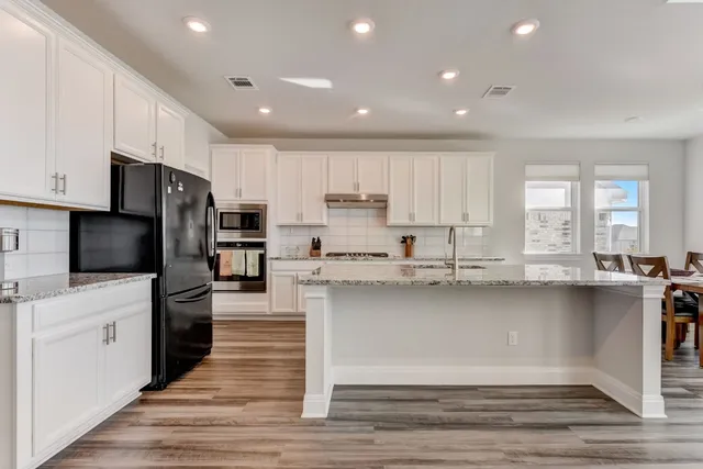 a large kitchen with cabinets in it and wooden floors