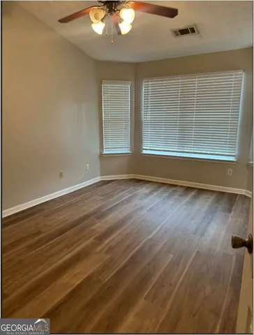 an empty room with wooden floor and windows