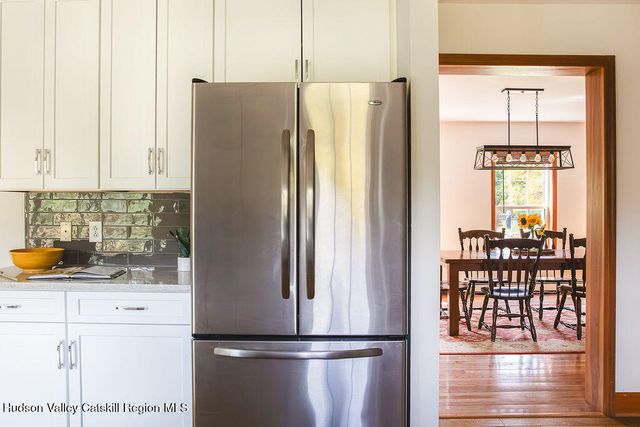 a kitchen with stainless steel appliances granite countertop a refrigerator and a wooden floors