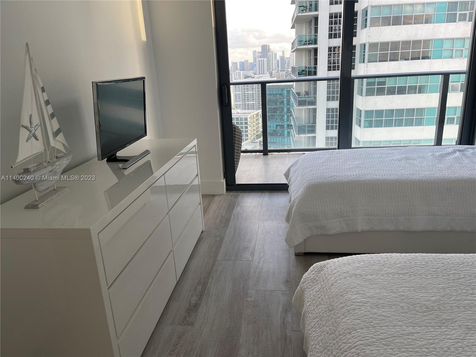 121 Northeast 34th Street, Unit 2802 Miami, FL 33137 - Photo 17 of 25 a room with a bed and a flat tv screen next to a window