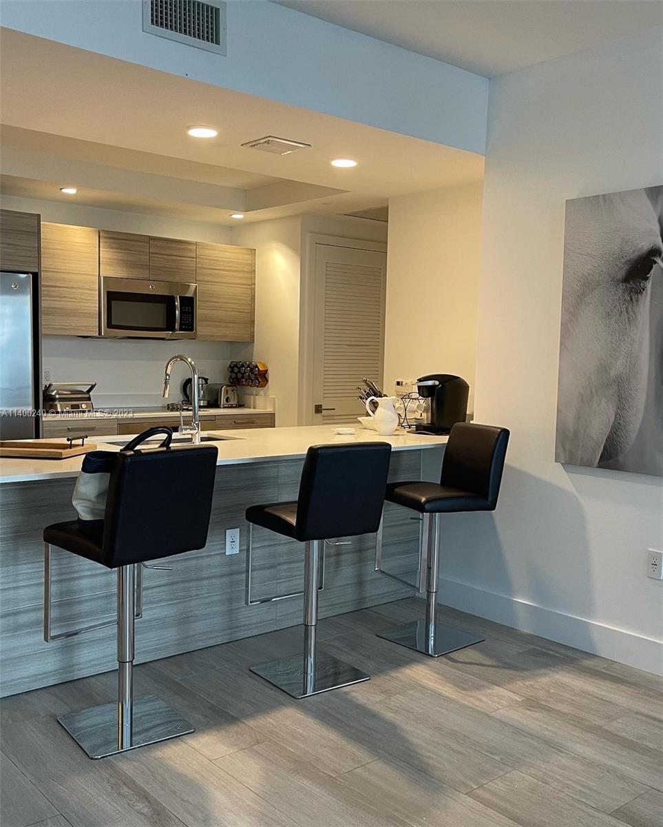 121 Northeast 34th Street, Unit 2802 Miami, FL 33137 - Photo 22 of 25 a kitchen with a sink and chairs