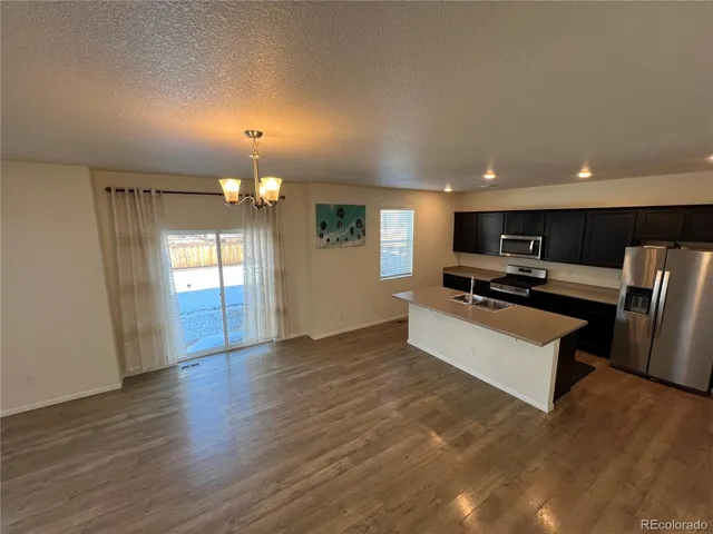 a view of kitchen with refrigerator stove and wooden floor