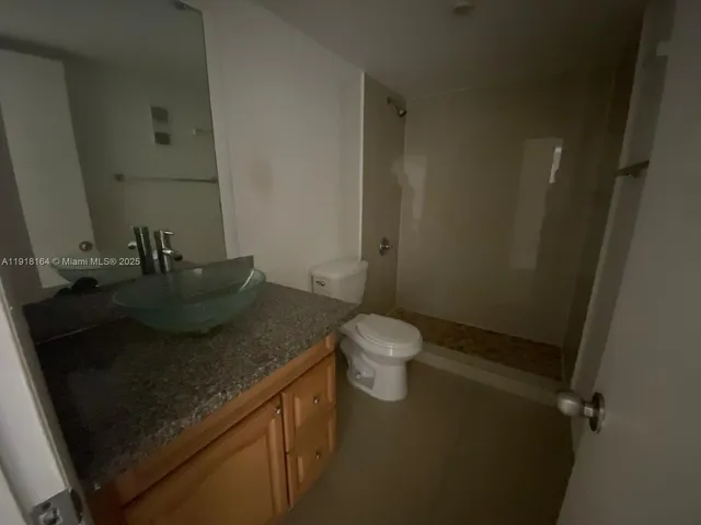 a bathroom with a granite countertop sink a toilet and a mirror