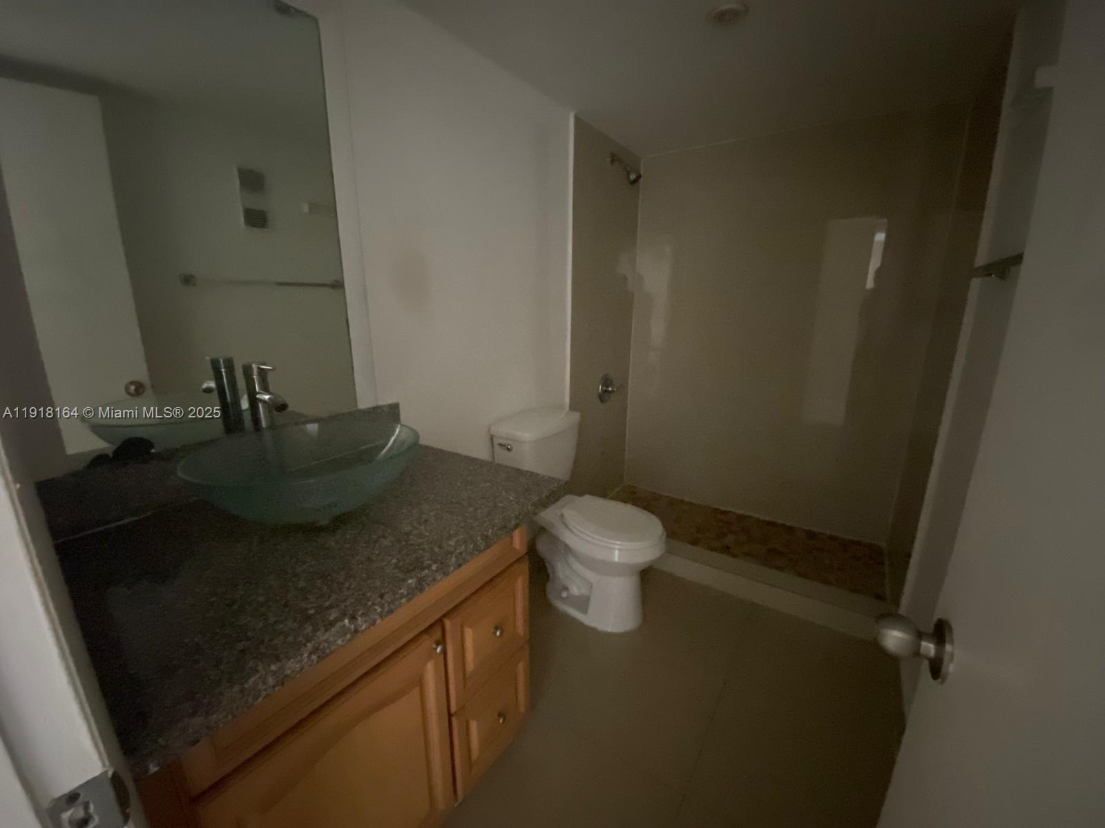 6970 Northwest 186th Street, Unit 3410 Hialeah, FL 33015 - Photo 6 of 10 a bathroom with a granite countertop sink a toilet and a mirror