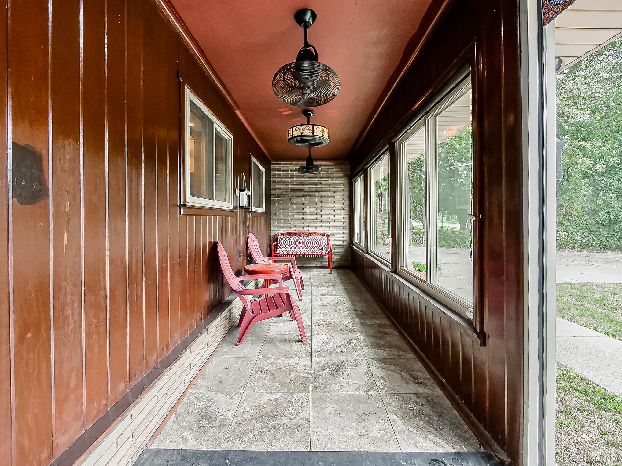 28177 Ryan Road Warren, MI 48092 - Photo 32 of 41 Enclosed porch featuring wood paneling, tiled flooring, full-length windows, and two ceiling fans with integrated lighting