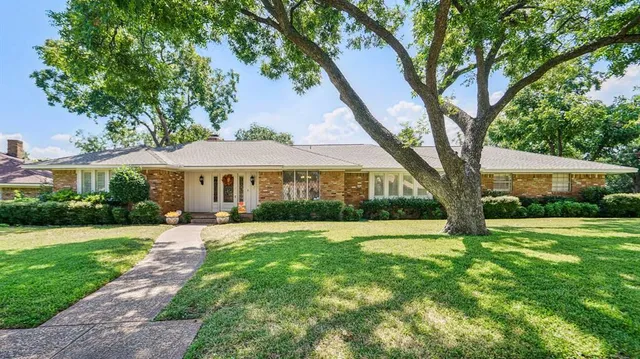 a front view of a house with yard and tree