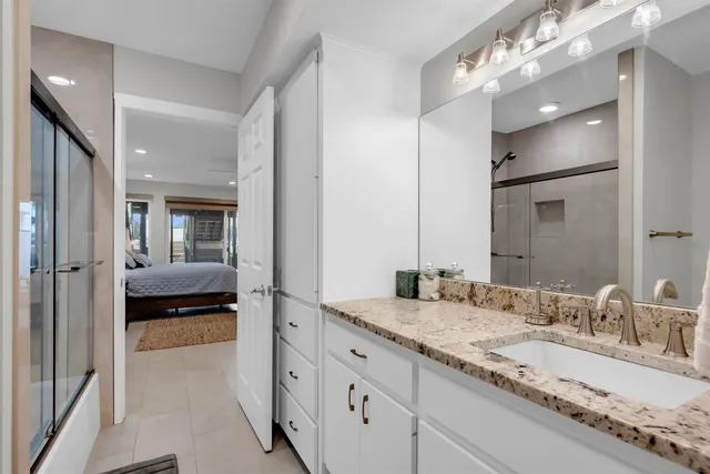a en suite bathroom with a granite countertop double vanity sink a mirror and shower