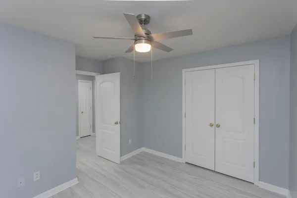 a view of an empty room with window and a ceiling fan