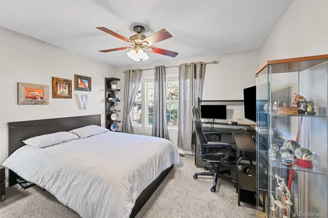 a bedroom with a bed a computer on a desk and a book shelf