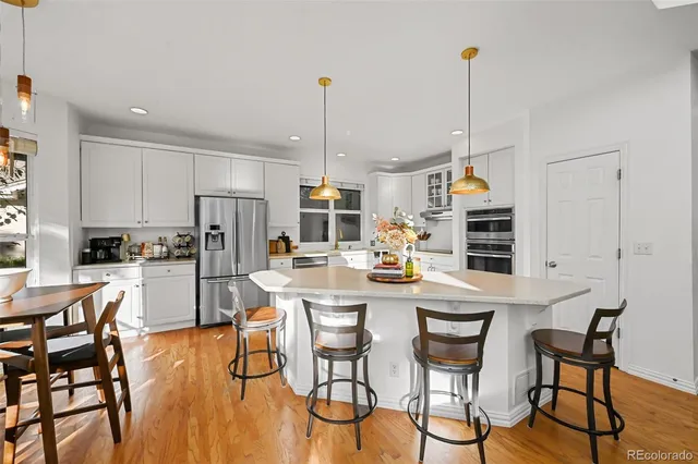 a kitchen with stainless steel appliances a dining table chairs and white cabinets