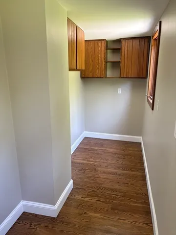 a view of an empty room with wooden floor and cabinet