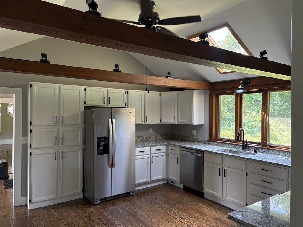208 Greenfield Road Deerfield, MA 01373 - Photo 6 of 28 a kitchen with granite countertop a refrigerator a sink dishwasher a stove and white cabinets with wooden floor