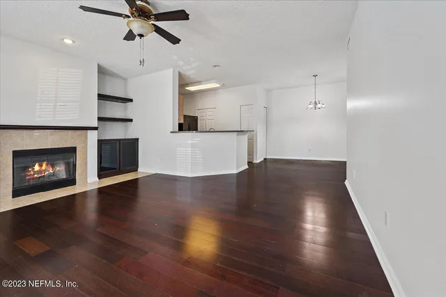 a view of a kitchen and an empty room with wooden floor