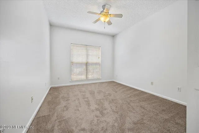 an empty room with a window and chandelier fan