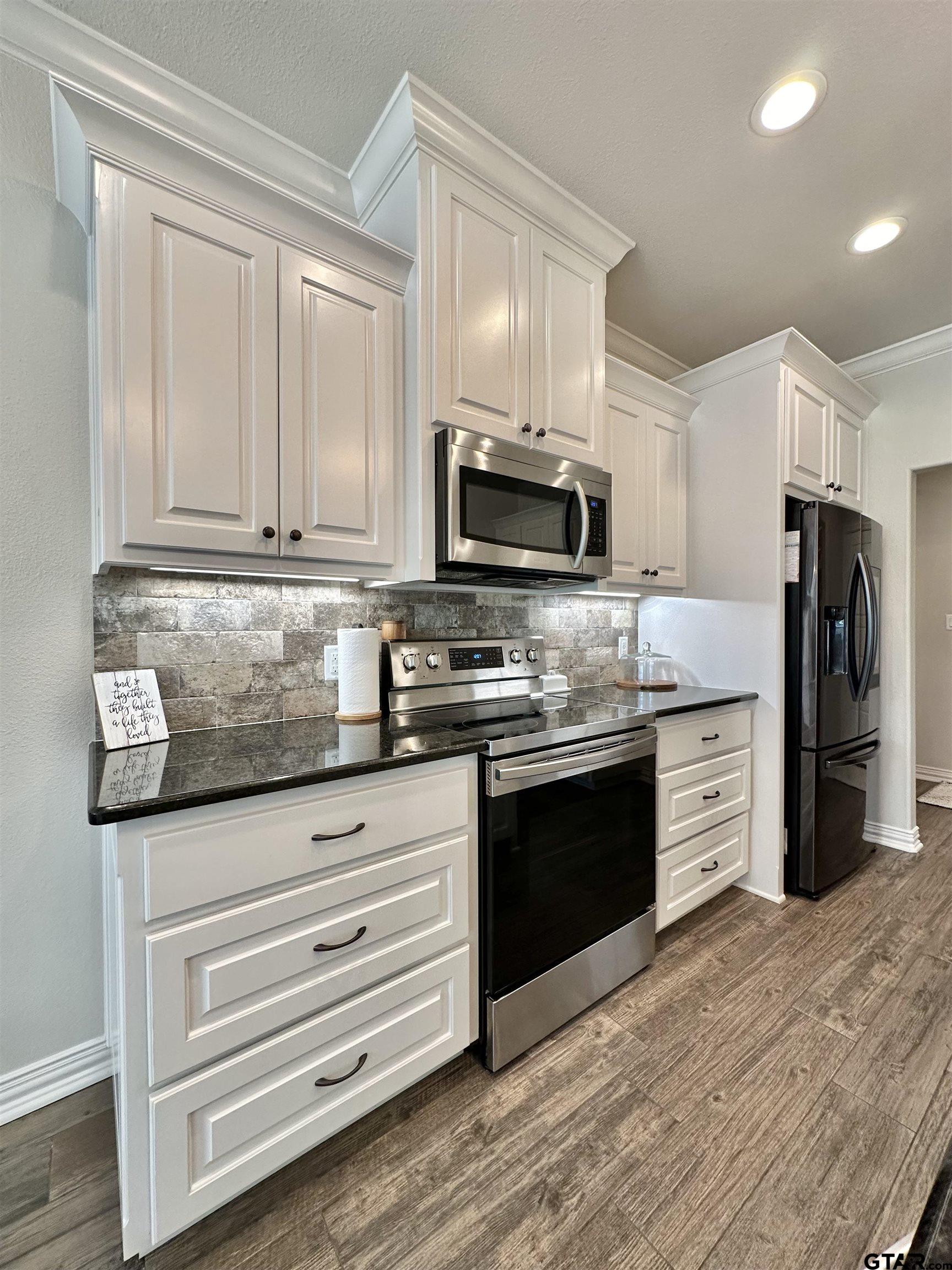 345 Willow Creek Ranch Road Gladewater, TX 75647 - Photo 21 of 47 a kitchen with granite countertop a refrigerator stove and wooden cabinets