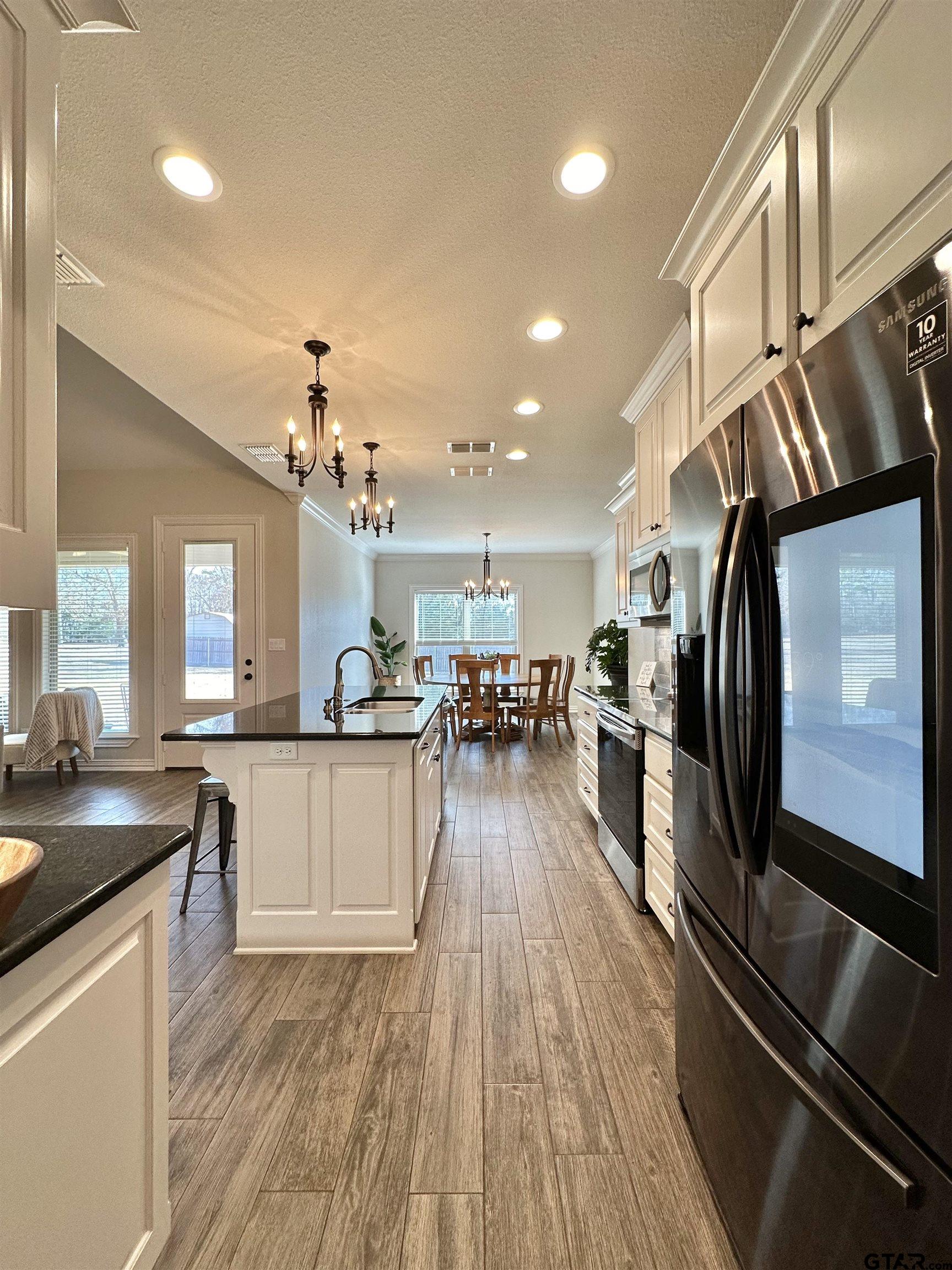 345 Willow Creek Ranch Road Gladewater, TX 75647 - Photo 22 of 47 a kitchen with stainless steel appliances granite countertop a refrigerator a sink dishwasher a stove and white countertops with wooden floor