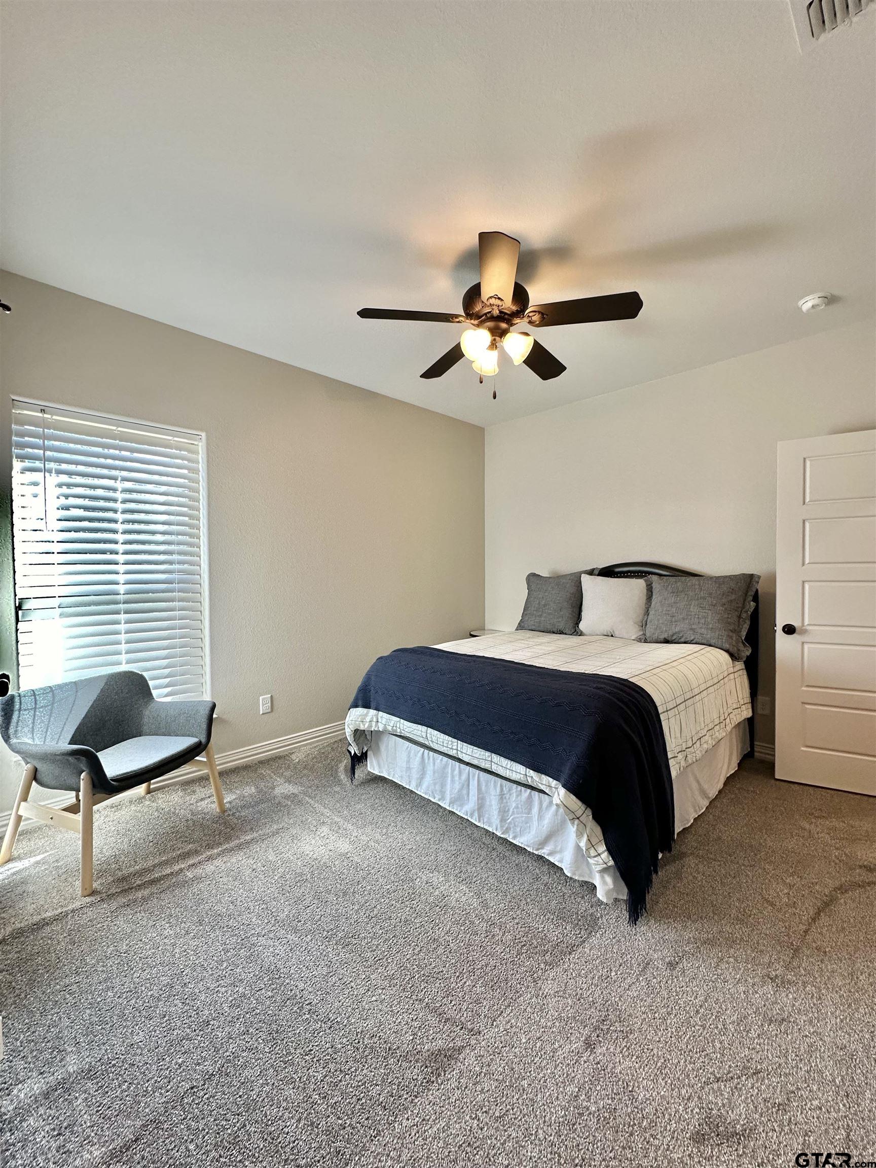 345 Willow Creek Ranch Road Gladewater, TX 75647 - Photo 44 of 47 a bedroom with a bed and a chandelier