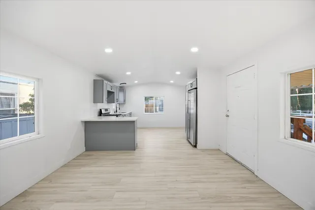 a view of a kitchen with kitchen island a sink wooden floor and a refrigerator