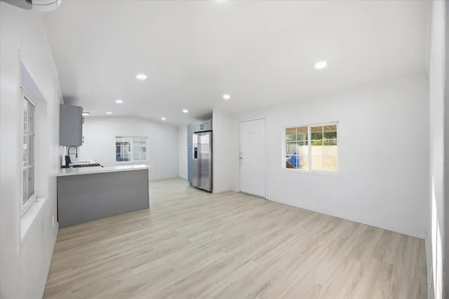 a view of a kitchen with kitchen island a sink wooden floor and a large window
