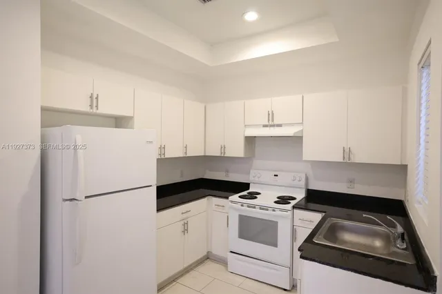 a kitchen with a refrigerator stove and white cabinets