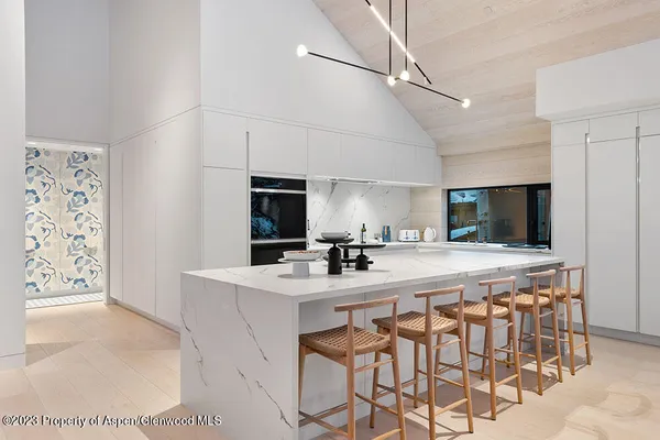 a kitchen with stainless steel appliances a sink a stove a refrigerator cabinets and chairs