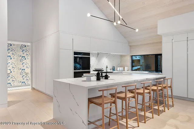 a kitchen with stainless steel appliances a sink a stove a refrigerator cabinets and chairs