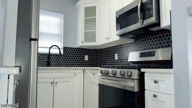a kitchen with granite countertop white cabinets and stainless steel appliances