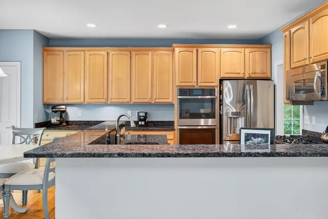 a kitchen with stainless steel appliances granite countertop a stove a sink a microwave a refrigerator and island
