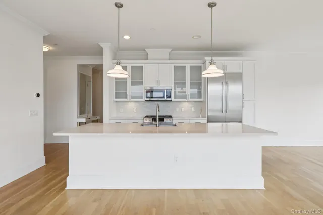 a view of a kitchen with kitchen island a sink stainless steel appliances and cabinets