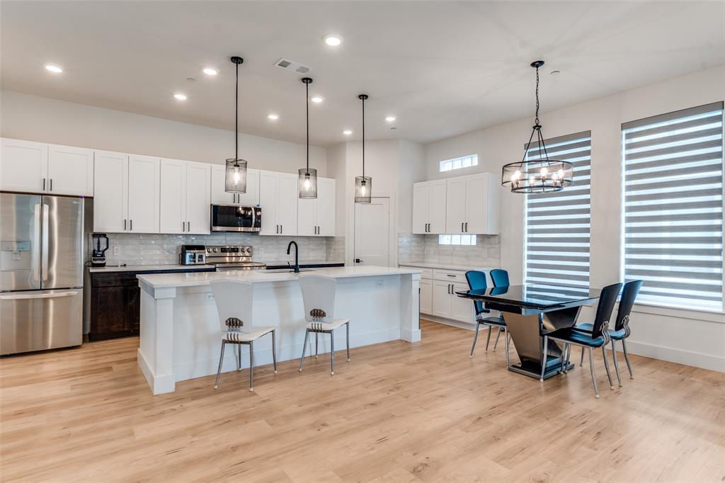 2134 Shea Road, Unit 1001 Dallas, TX 75235 - Photo 5 of 12 a kitchen with stainless steel appliances granite countertop a refrigerator a stove a sink dishwasher a dining table and chairs with wooden floor