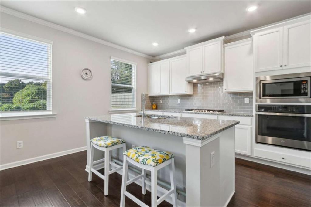 429 Paxton Lane Jefferson, GA 30549 - Photo 23 of 53 a kitchen with granite countertop stainless steel appliances a stove a sink a microwave a refrigerator and white cabinets with wooden floor