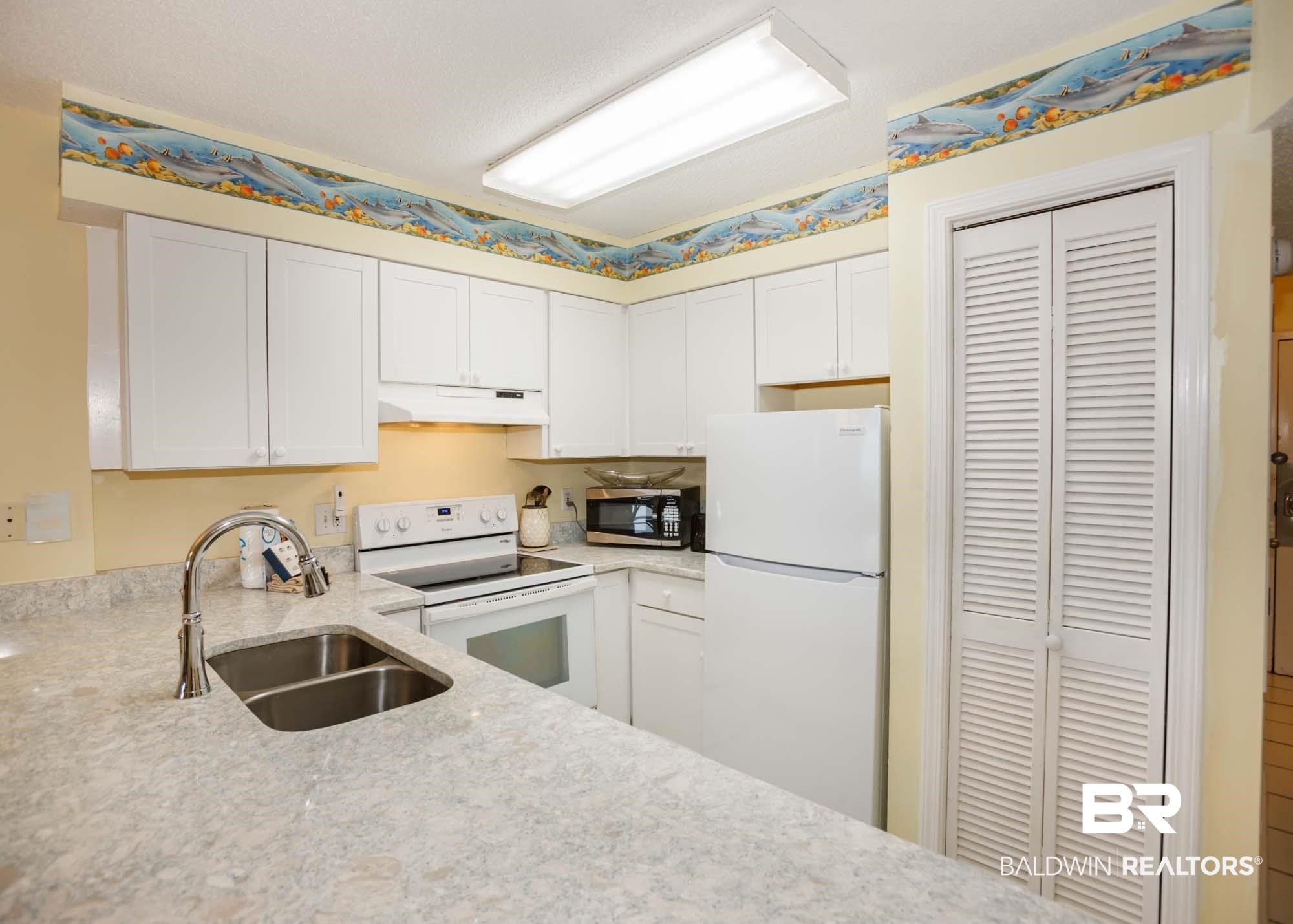 645 Plantation Road, Unit 6311 Gulf Shores, AL 36542 - Photo 39 of 43 Kitchen with white appliances, under cabinet range hood, a sink, light stone counters, and white cabinetry