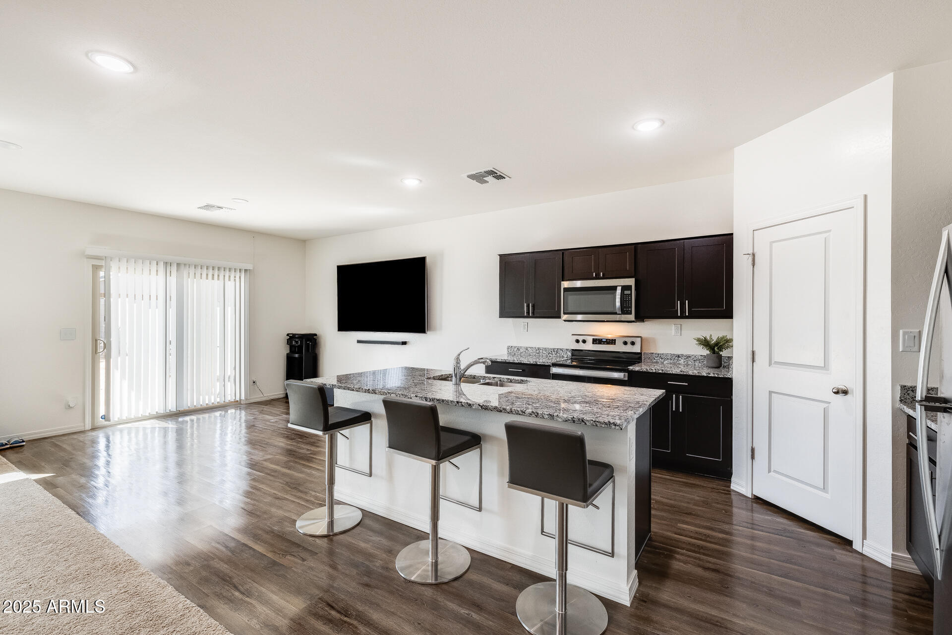 5663 East Moira Road Florence, AZ 85132 - Photo 11 of 37 a open kitchen with stainless steel appliances kitchen island granite countertop a stove top oven a sink dishwasher and a refrigerator with wooden floor