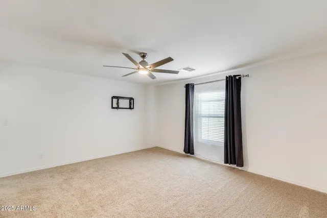 an empty room with a ceiling fan and carpet