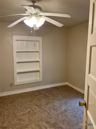 en empty room with a window and ceiling fan