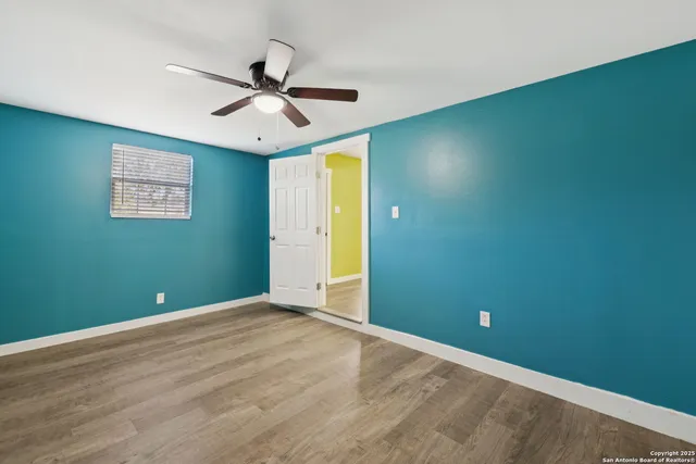an empty room with a ceiling fan and window