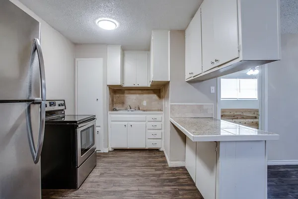 a kitchen with granite countertop a sink stove and refrigerator