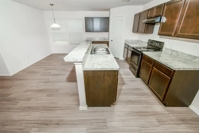 a kitchen with stainless steel appliances granite countertop a sink stove and wooden floor