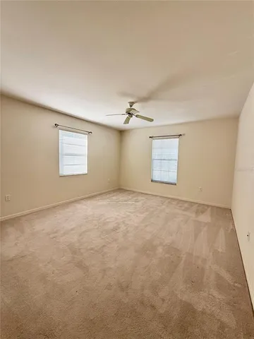 an empty room with windows and ceiling fan view